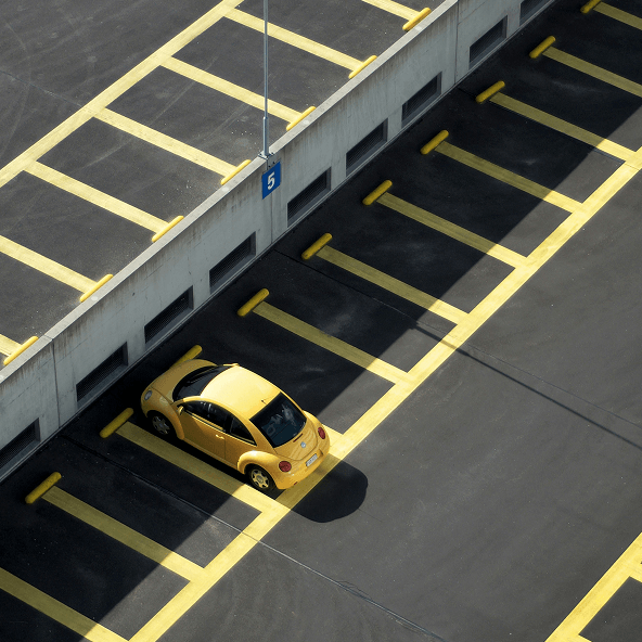 Zółty samochód na parkingu z wieloma obrysowanymi miejscami parkingowymi w żółtym kolorze